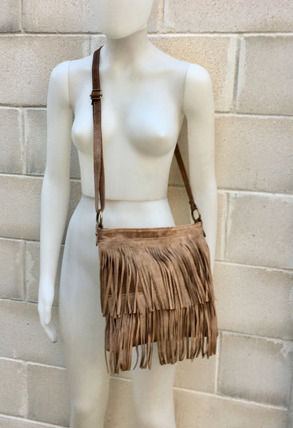 May include: A brown suede crossbody bag with fringe detailing.