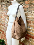 May include: A brown suede tote bag with a brown leather strap.