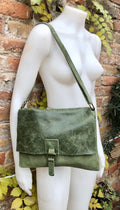 May include: A green leather crossbody bag with a flap closure and a buckle. The bag has a distressed look and a long strap.